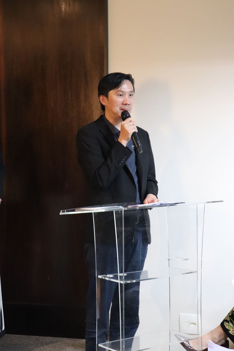 Leandro Su, Vice President of IECBC, speaks into the microphone at the lectern during the meeting.